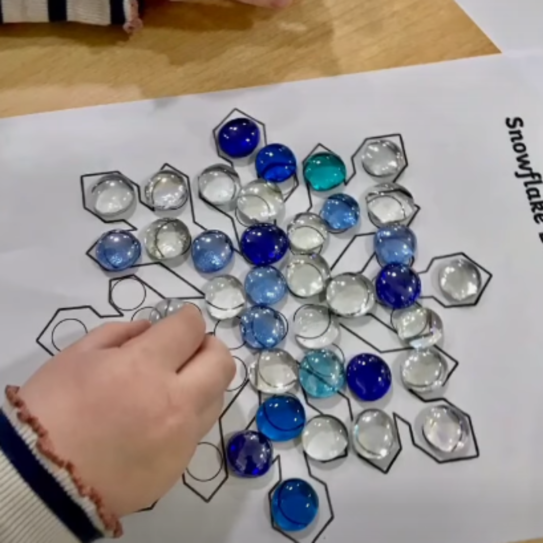 placing blue and clear beads onto a paper snowflake design to improve fine motor skills